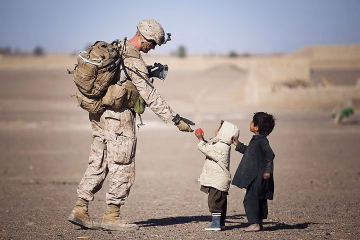marine-sharing-a-moment-with-local-children-in-a-d - HeroThemes Marine sharing a moment with local children in a desert village